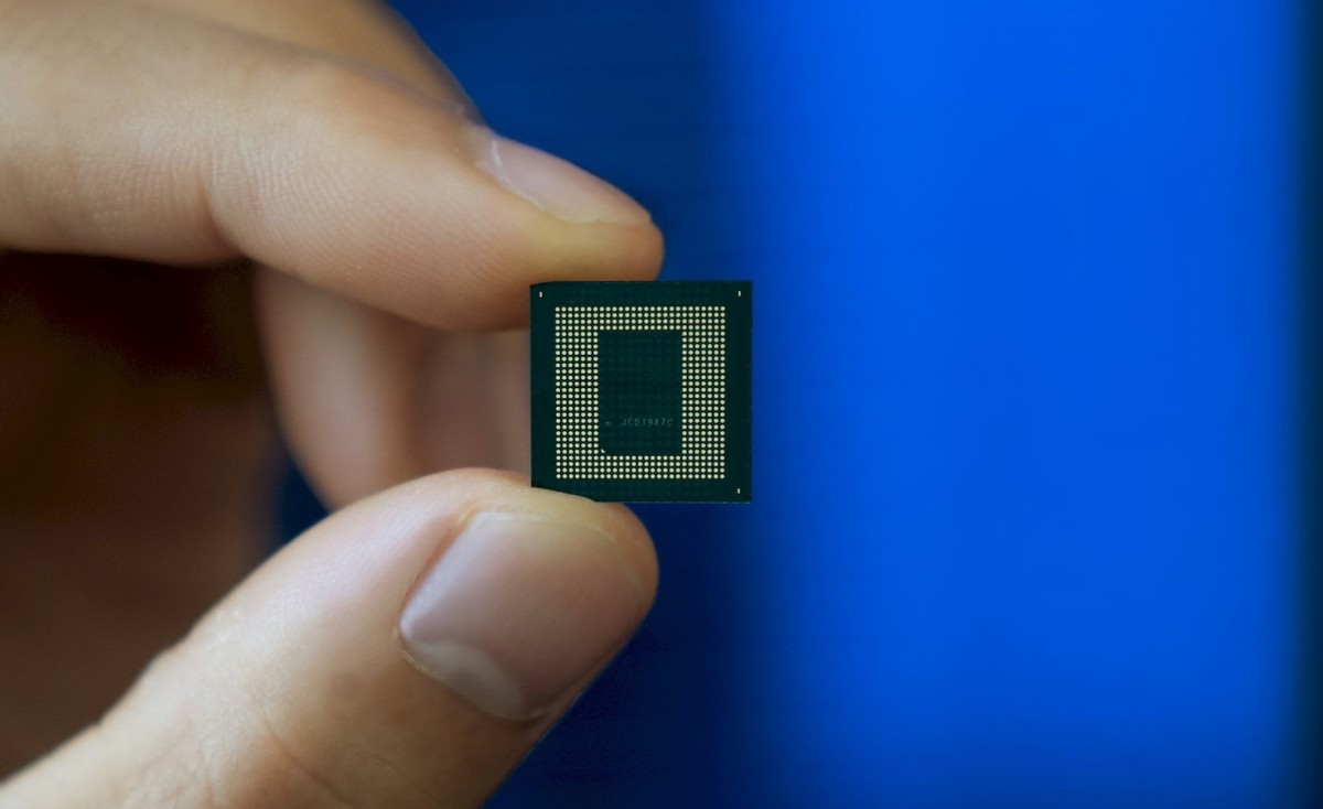  A hand holding a small green and black Snapdragon 8 Gen 3 chipset with text that reads 'Qualcomm Snapdragon 8 Gen 3' in front of a blue background.