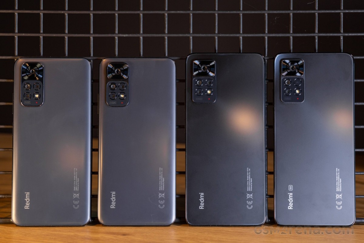  Four Xiaomi Redmi Note 11 NFC smartphones in different colors lined up on a wooden surface against a dark background.